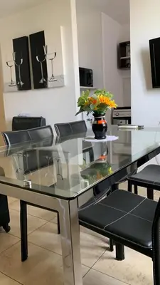 a glass table with chairs and a vase with flowers on it at Moderno Departamento Acogedor in Cordoba