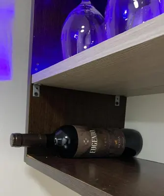 a bottle of wine sitting on a shelf with wine glasses at Moderno Departamento Acogedor in Cordoba