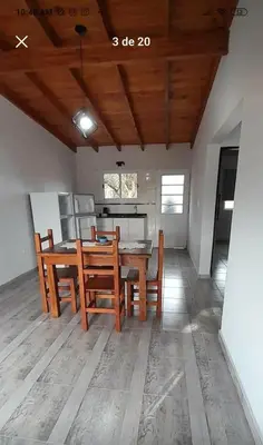 a dining room with a table and chairs and a kitchen at La casita de Emilia in Los Molles