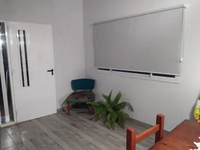 a white room with a chair and a tv on a wall at La casita de Emilia in Los Molles