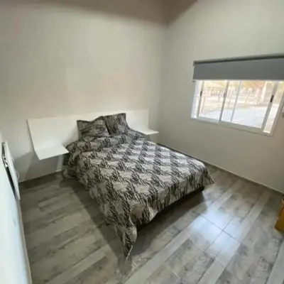 a bedroom with a bed with a comforter and a window at La casita de Emilia in Los Molles