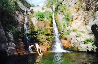 a person in the water next to a waterfall at Depto Av del Sol in Merlo
