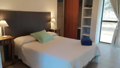 a bedroom with a white bed with a blue bag on it at Indigo in Carpintería
