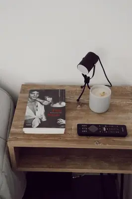 a table with a remote control and a book and a lamp at Departamento NYC 1 - Edificio VILAUT by INMOVE Temporarios in Cordoba