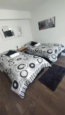 two beds with black and white covers in a room at Departamento NYC 1 - Edificio VILAUT by INMOVE Temporarios in Cordoba