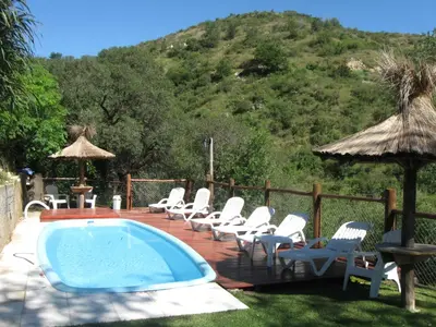 a deck with chairs and a swimming pool with a mountain at Moradillo Apart in La Cuesta