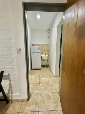 a hallway with a refrigerator and a table in a room at ACOGEDOR Dpto Pasaje Tucumán in Alta Gracia
