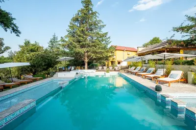 a pool with chairs and umbrellas next to a resort at LAS PRINCESAS Cabañas frente al rio in Los Reartes