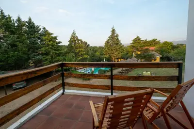 a balcony with two chairs and a view of a pool at LAS PRINCESAS Cabañas frente al rio in Los Reartes