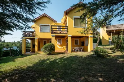 a yellow house with a yard in front of it at LAS PRINCESAS Cabañas frente al rio in Los Reartes