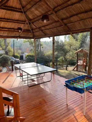 a patio with two ping pong tables and a gazebo at LAS PRINCESAS Cabañas frente al rio in Los Reartes