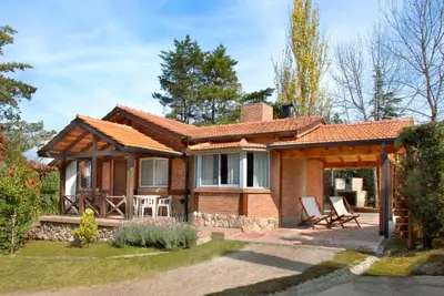 a brick house with a porch and chairs at Samai Suma Cabañas & Spa in Villa General Belgrano