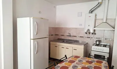 a kitchen with a white refrigerator and a table at Departamentos Buena Onda in Villa Carlos Paz