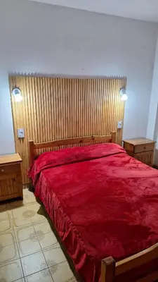 a bedroom with a red bed with two night stands at Departamentos Buena Onda in Villa Carlos Paz