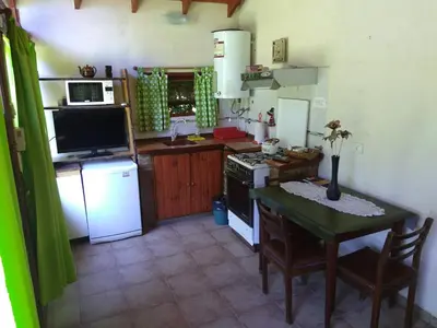 a kitchen with a table and a stove and refrigerator at Cabaña Los Angeles in Villa General Belgrano