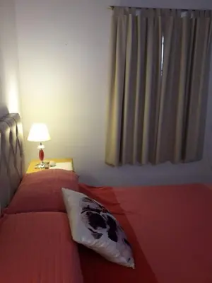 a bedroom with a red bed with a pillow and a lamp at Casa del Sol in Santa María