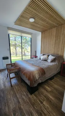 a bedroom with a large bed and a large window at Colores de Manantiales in Villa General Belgrano