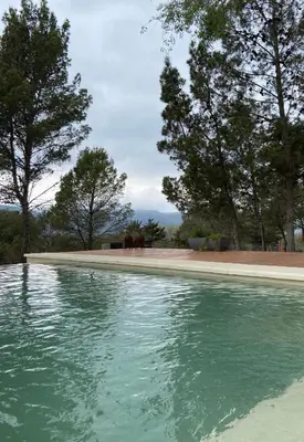 a pool of water with trees in the background at Colores de Manantiales in Villa General Belgrano