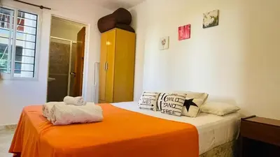 a bedroom with a bed with an orange blanket at Deptos carlos paz in Villa Carlos Paz
