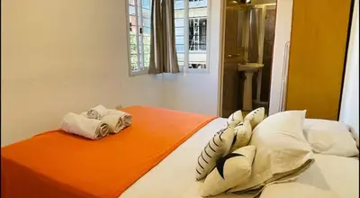 a bed with two pillows and an orange blanket at Deptos carlos paz in Villa Carlos Paz