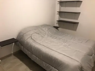 a bed in a room with two shelves at Deptos carlos paz in Villa Carlos Paz