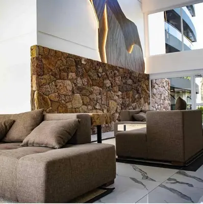 a living room with two couches and a stone wall at Departamento Veneto Village - K - in Villa Parque Siquiman