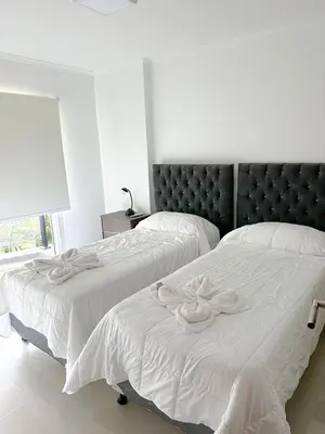 two beds in a bedroom with white sheets at Departamento Veneto Village - B in Villa Parque Siquiman