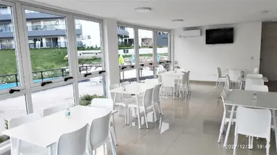 a restaurant with white tables and chairs and windows at Departamento Veneto Village - B in Villa Parque Siquiman