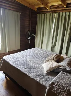 a bedroom with a bed and a window with curtains at Villa Nicolasa in Villa Yacanto