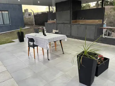 a table and chairs on a patio with plants at Casa Carlos Paz, 6 personas in Estancia Vieja