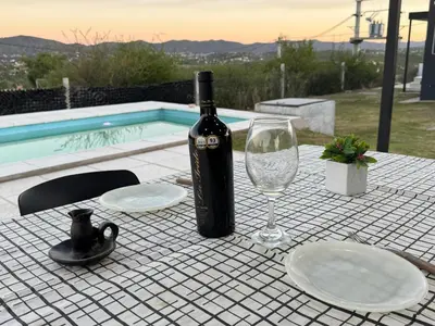 a bottle of wine sitting on a table with a glass at Casa Carlos Paz, 6 personas in Estancia Vieja