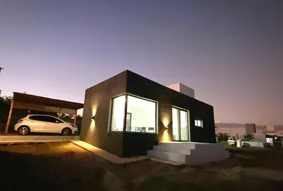 a small house with a car parked in a parking lot at Casa Carlos Paz, 6 personas in Estancia Vieja