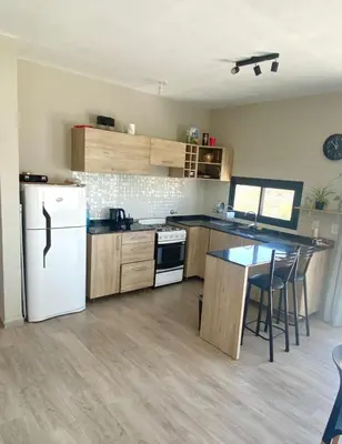 a kitchen with a white refrigerator and a table at Casa Carlos Paz, 6 personas in Estancia Vieja