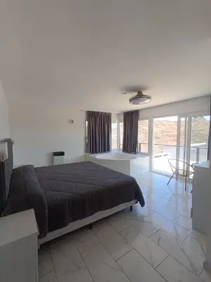 a bedroom with a large bed and a living room at Aire de las Sierras in Embalse