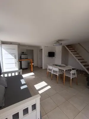 a living room with a table and chairs and a staircase at Aire de las Sierras in Embalse