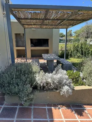 a garden with a bench under a wooden pergola at Cabaña Sierras Chicas in Villa Anizacate