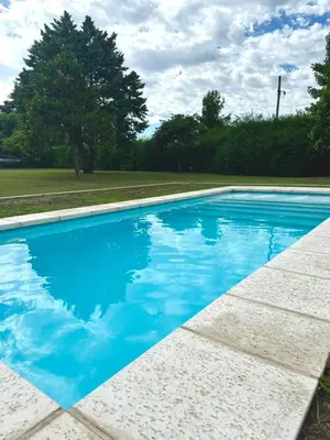 a swimming pool with blue water in a yard at Cabaña Sierras Chicas in Villa Anizacate