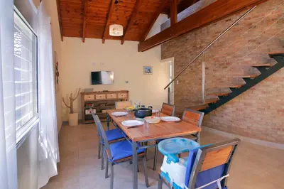 a dining room with a wooden table and blue chairs at Cabaña para relajarse con vista panorámica in Villa General Belgrano