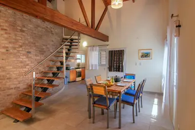a dining room with a table and chairs and a staircase at Cabaña para relajarse con vista panorámica in Villa General Belgrano