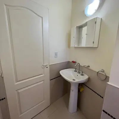 a bathroom with a sink and a mirror and a door at Dorrego Departamentos in Villa Dolores