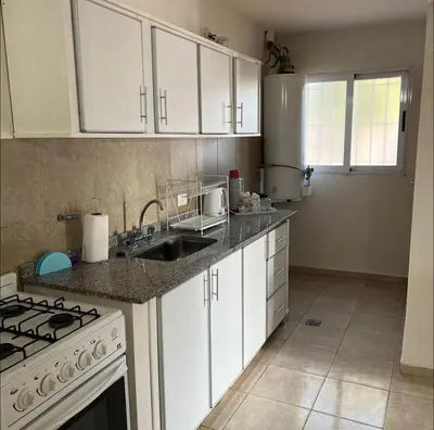a kitchen with white cabinets and a sink and a stove at Dorrego Departamentos in Villa Dolores
