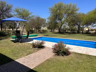 a blue swimming pool with a blue umbrella and a chair and an umbrella at Casa Valle del colibrí in Cañada La Negra