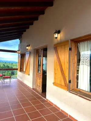 a porch of a house with wooden doors and a patio at Cabañas Casa Flor Yacanto in Villa Yacanto