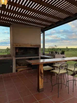 a table and chairs on a patio with a fireplace at Cabañas Casa Flor Yacanto in Villa Yacanto