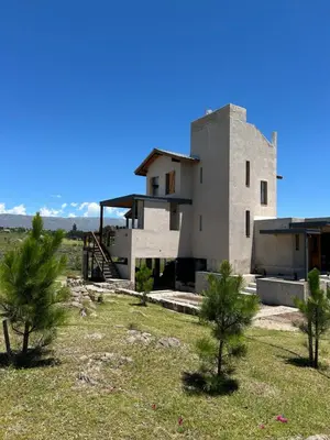 a house in the middle of a field with trees at Cabañas Casa Flor Yacanto in Villa Yacanto