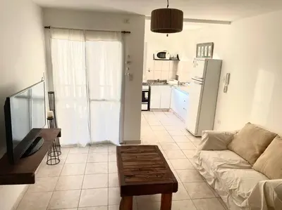 a living room with a couch and a table and a kitchen at Departamento en Alberdi in Cordoba