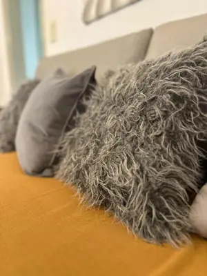 a couch with pillows and a gray blanket at CASA Q Cba Zona Norte Kempes Aeropuerto Shopping cochera asador patio full equipada confortable in Cordoba