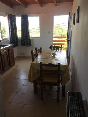 a dining room with a table and chairs and windows at Depto temporario carlos paz in Villa Carlos Paz