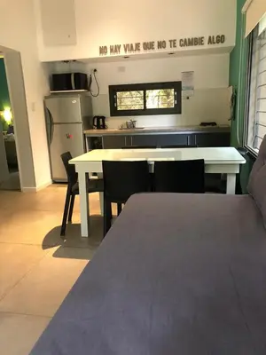 a kitchen with a white table and chairs and a kitchen with a refrigerator at Cabañas Apart Margaridas in Merlo