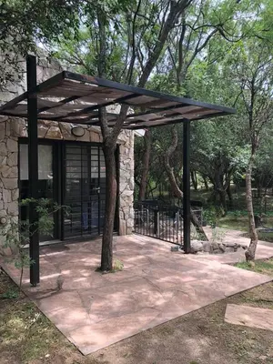 a pavilion with a tree in front of a building at Cabañas Apart Margaridas in Merlo